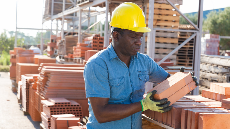 A man stacking bricks in a brickyard.