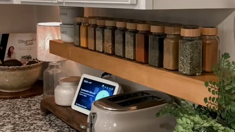 Spice bottles sitting on a floating shelf mounted above the countertop