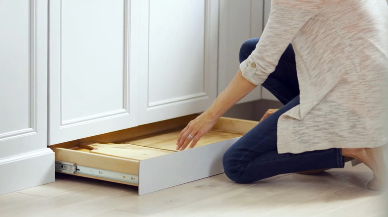Woman retrieving a cutting board from a toe kick drawer