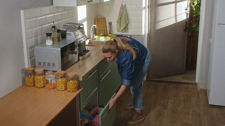 Woman opening a lower kitchen cabinet