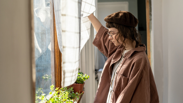 A woman in a brown outfit looks out of a window
