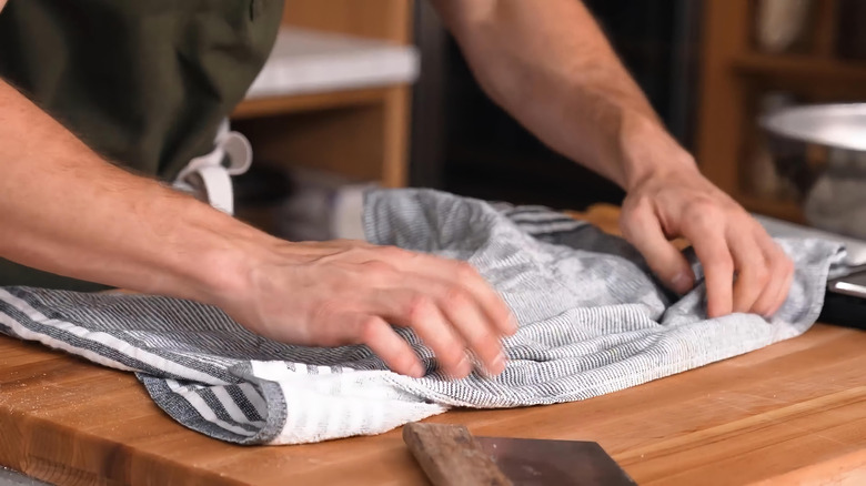 Person using a striped towel on a kitchen countertop