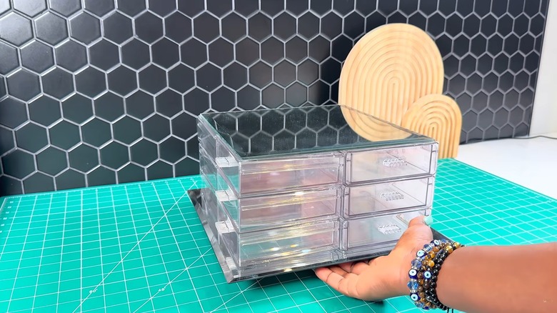 Woman cupping finished elegant bathroom organizer on teal cutting mat with geometric back backsplash on countertop