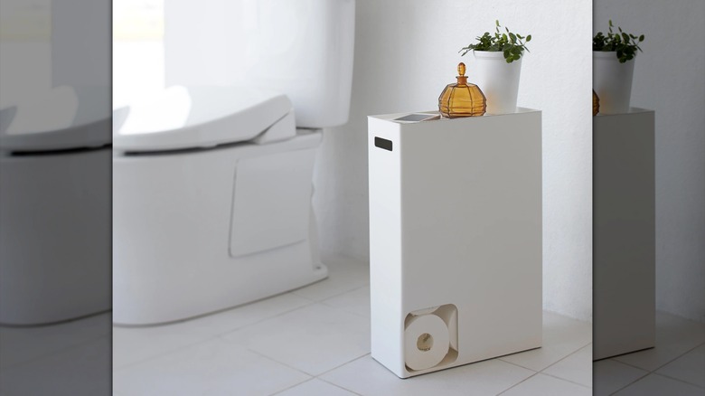 White Yamazaki Home Toilet Paper Stocker in minimalist bathroom next to toilet