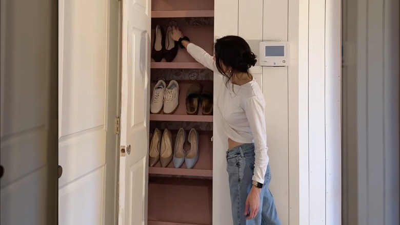 A woman places a pair of shoes on a pink custom closet shelf