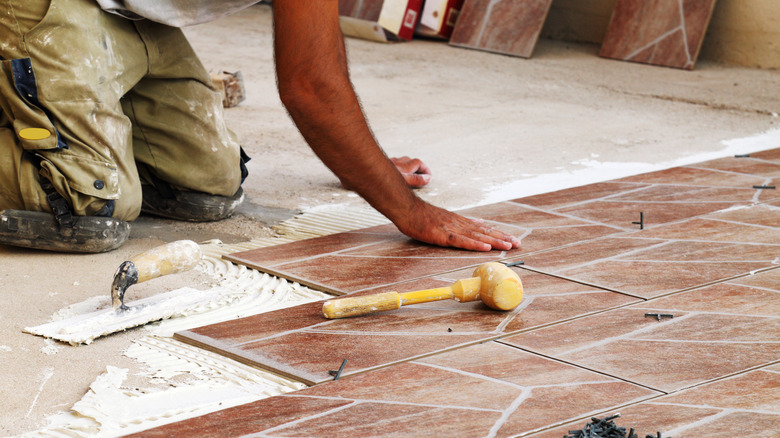 A person lays porcelain floor tiles.