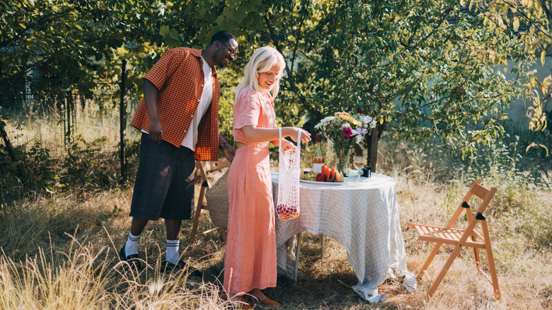 A young couple sets a table outdoors