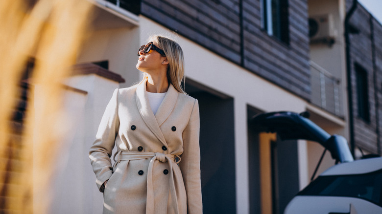 A woman stands in her driveway on a sunny day
