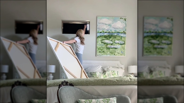 A woman covering a narrow window with canvas art