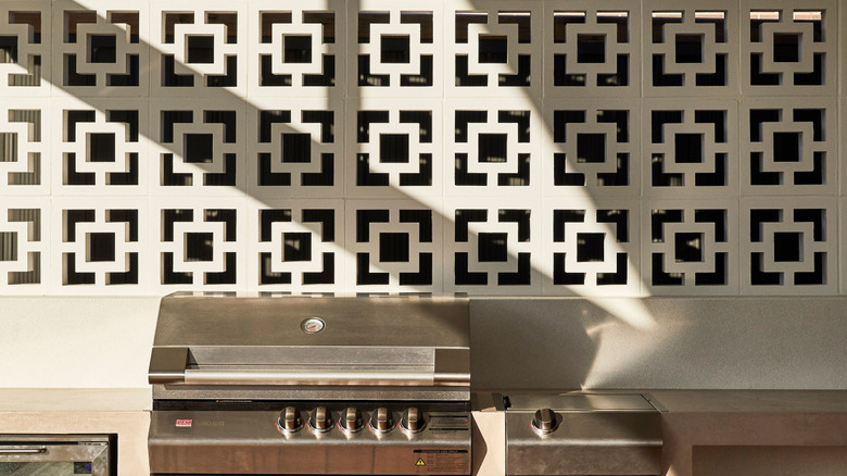 A grey breeze block wall behind grill and outdoor kitchen allows air through while providing privacy.