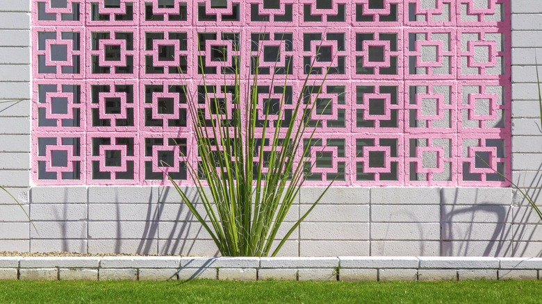 Pink breeze blocks set into grey cinder block wall add a pop of color to a home.