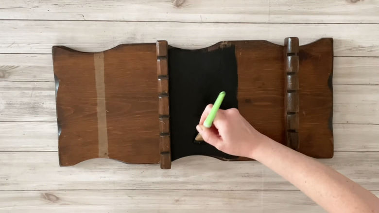 A hand painting a vintage wood spoon rack