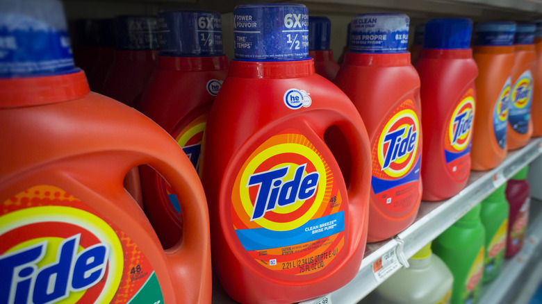 Orange bottles of Tide laundry detergent sit on a shelf