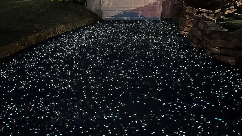 A top-down view of a driveway glowing with bright blue stones