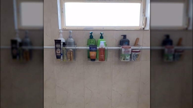 Plastic bins threaded onto a tension rod in a shower with various bottles in the bins