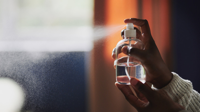 Hands spritzing spray bottle.