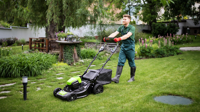 Man cutting grass with a push lawn mower.