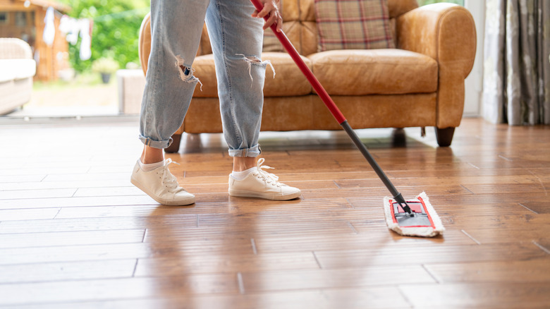 Person using a dry mop on a hardwood floor