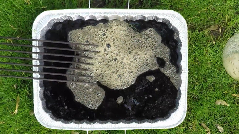 A grill grate soaking in a pan of coffee