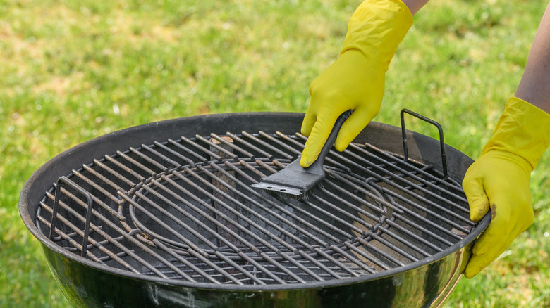 Person in gloves scrubbing a grill