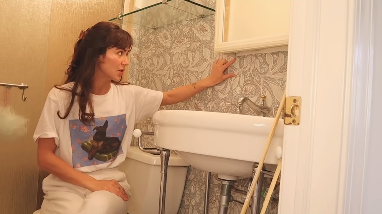 Woman planning storage solutions and decor in tiny home bathroom