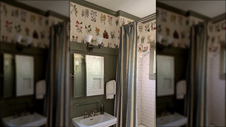 A bathroom with green wainscoting and floral book pages used as wallpaper