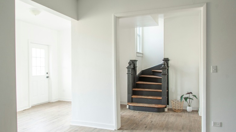 An empty house with white walls and a wooden and black staircase