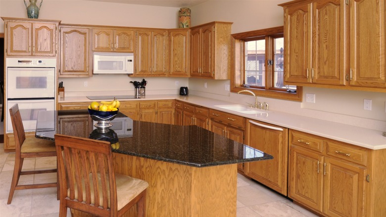 Household kitchen with white appliances and dated wood cabinetry