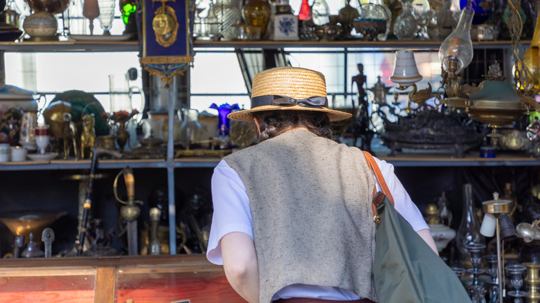 Person in straw hat shopping at antique store