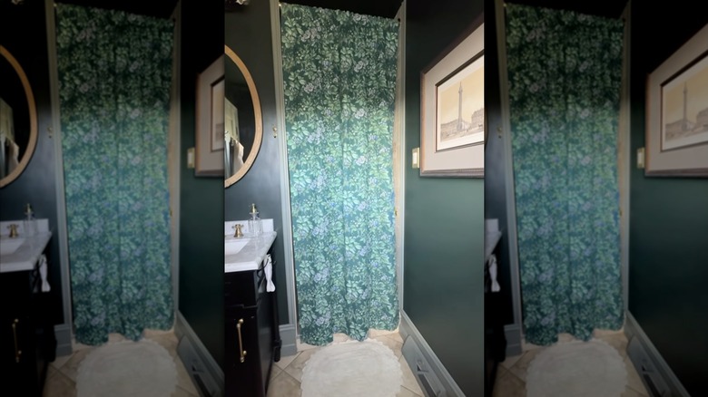 A green bathroom with a green floral shower curtain