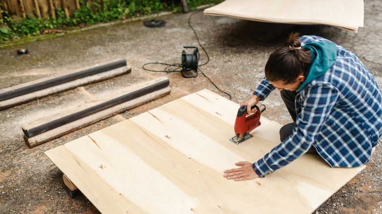 Man cutting plywood in his backyard