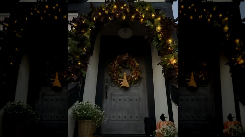 A fall doorway and decorative floral arch at night