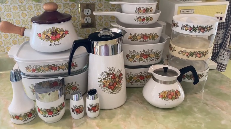 Large collection of Spice o' Life casserole dishes, saucers, shakers, and storage containers on stone countertop in vintage kitchen