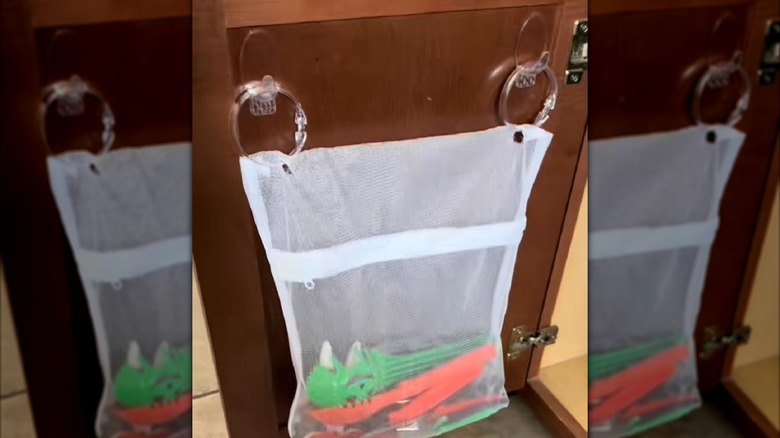 Dollar Tree mesh bag hung on back of cabinet door for organizational purposes