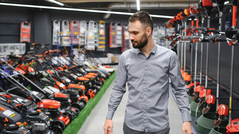 A person walking down a lawn tool aisle in a store