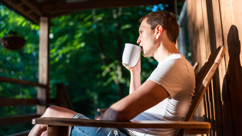 Man drinking a cup of coffee on his front porch
