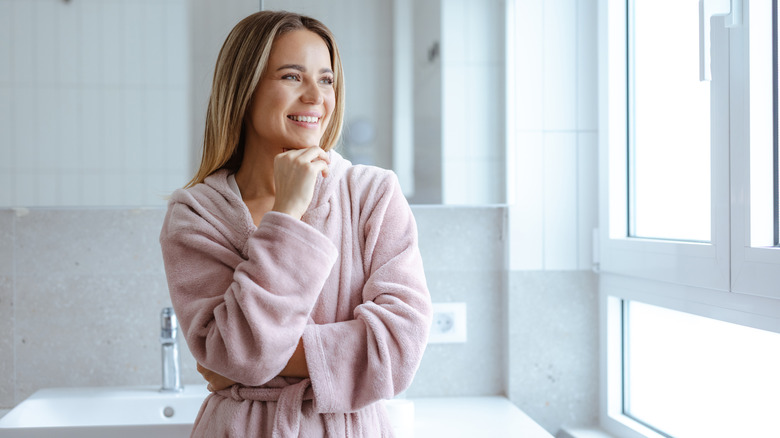 A woman smiles while thinking in the bathroom