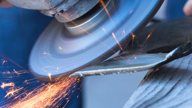 A lawnmower blade being sharpened with an angle grinder.