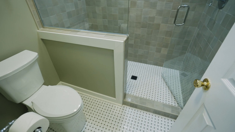 A shower room with basketweave tiled flooring, and a walk-in shower with zellige tiles
