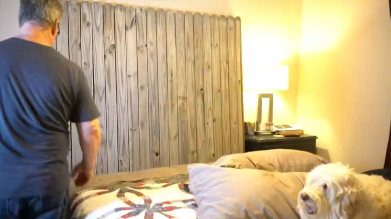 A headboard made of old fence paneling against the wall behind a bed