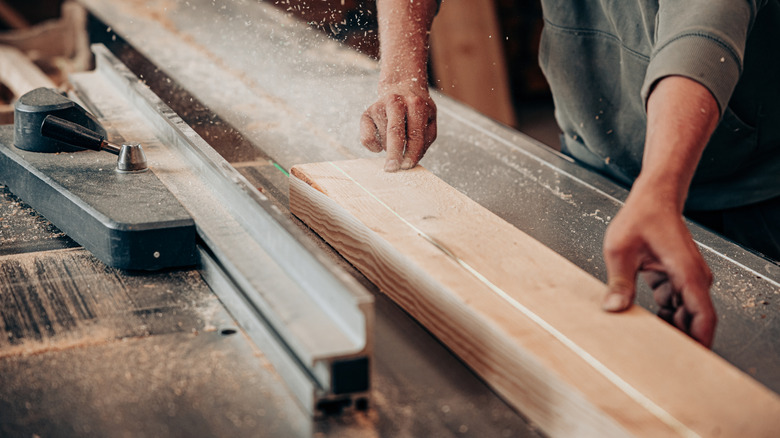Person using a saw to trim a wood board