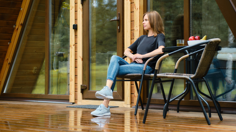 A woman sitting on a chair on a wet deck after te rain
