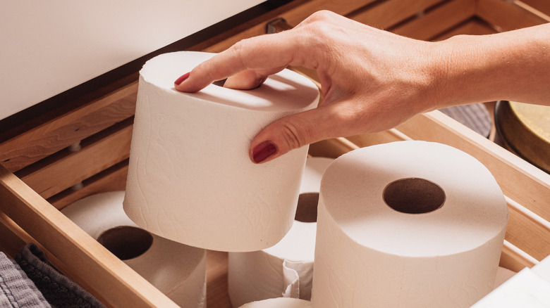 Person putting toilet paper in a drawer