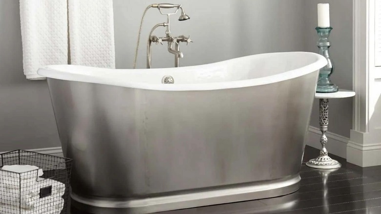 A chrome bathtub in a room with wood floors and grey walls