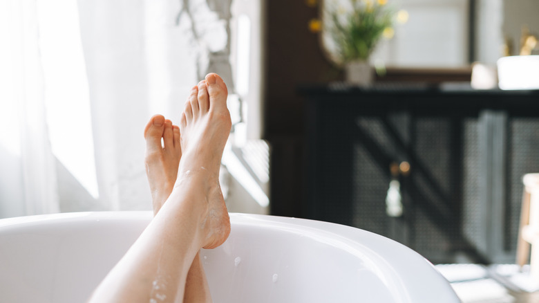 Two feet resting on rim of bathtub