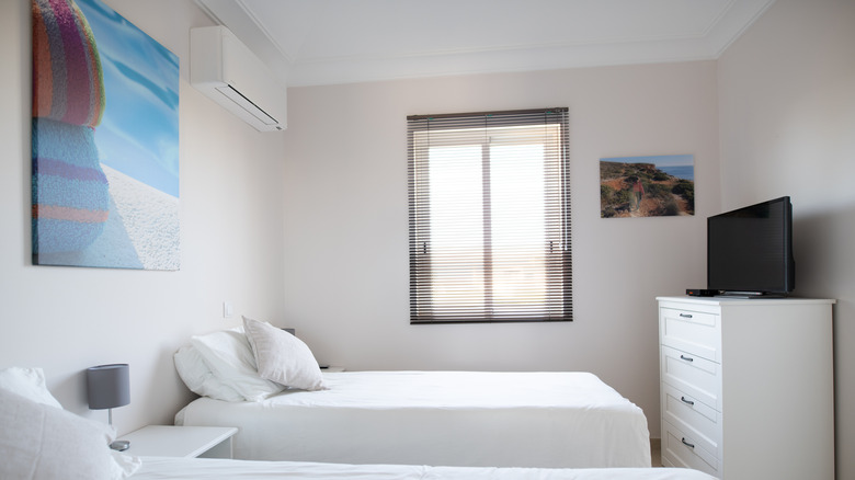 A minimalist bedroom with venetian blinds in a small window