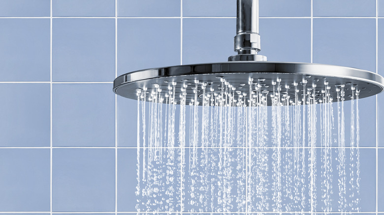 A clean rainfall shower head with flowing water.