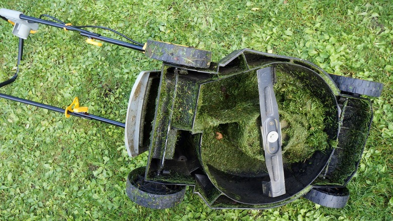 Upside down rotary mower showing grass buildup on underside