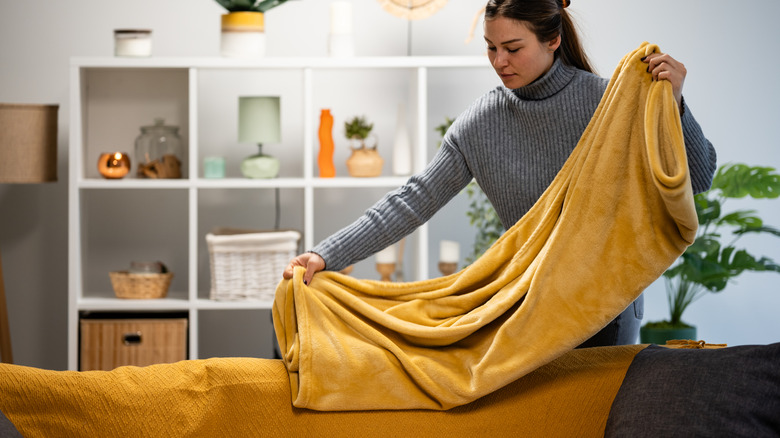 Woman folding a golden yellow throw blanket