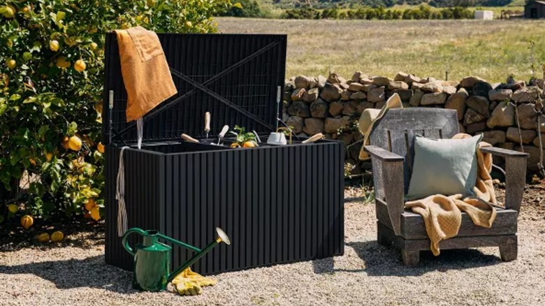 Veradek Everything Deck Box on gravel outdoor space next to deck chair.